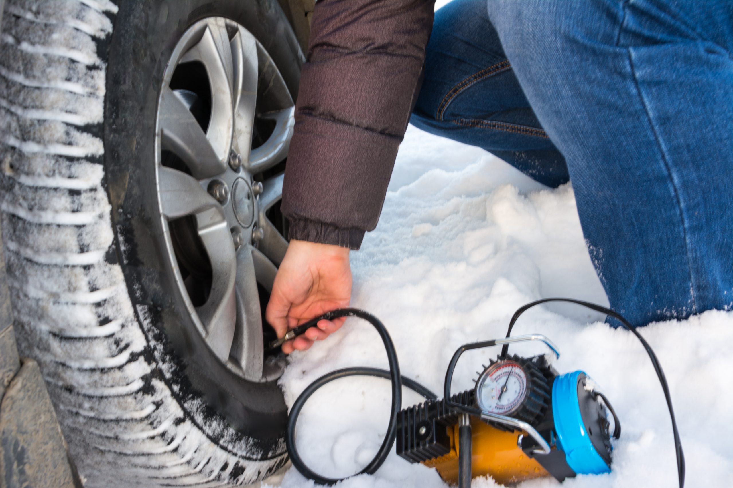 Filling air into a car tire. Filling air into a car tire. Winter. Closeup of a repairing a flat tire use compressor blower.