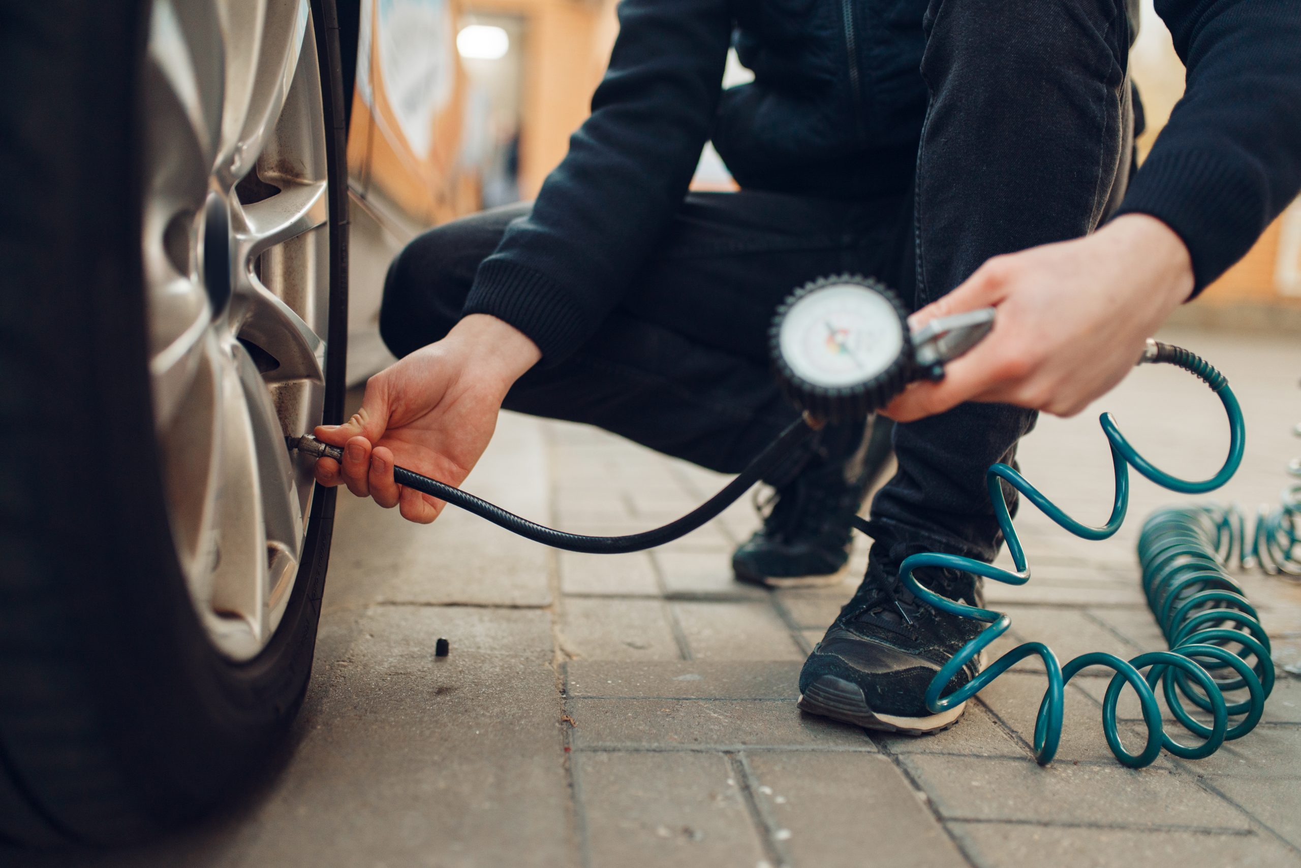 A man checking the tire pressure of a tire on his car. A man checking the tire pressure of a tire on his car.