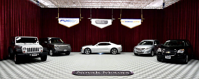 Showroom display from 2010 featuring five vehicles under Fusion Auto Finance, LRRC, and CU Xpress Lease banners—representing the launch of the first Lease Return & Resale Center.